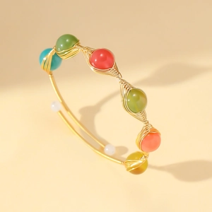Detailed close-up of wire-wrapped gold bracelet with colorful beads and strawberry quartz