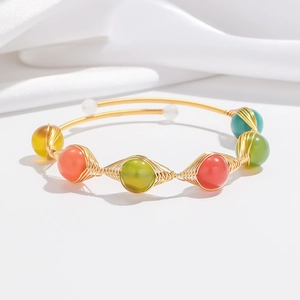 Detail of handmade gold wire-wrapped bracelet with colorful strawberry crystal beads