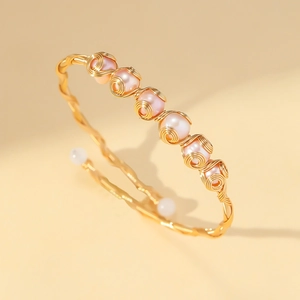 Nahaufnahme des handgefertigten Golddraht-Armreifs mit sieben rosa Perlen und Finish