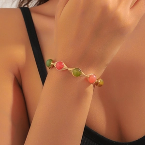 Close-up of handmade gold wire bracelet with colorful strawberry crystal and pearls