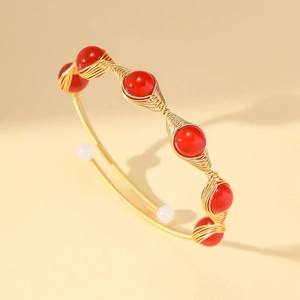 Detail of gold wire wrapped open bangle with red strawberry crystal beads and pearls