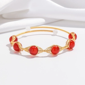 Detailed shot of handcrafted gold wire wrapped bangle with red beads and pearls