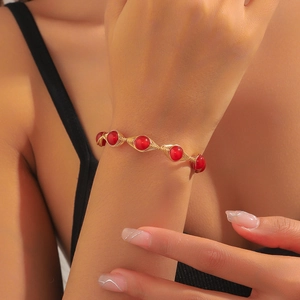 Detail of beaded bracelet with red gems wrapped in gold wire with handmade textures