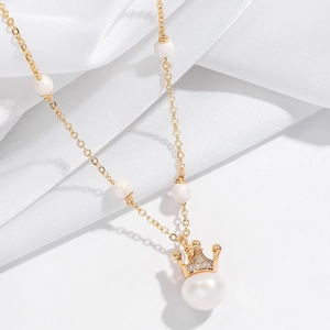 Elegant gold crown pendant necklace with natural freshwater pearls on a white silk background
