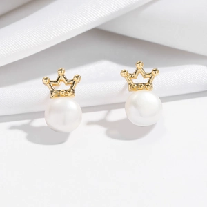 Elegant gold crown stud earrings featuring natural freshwater pearls on silk fabric