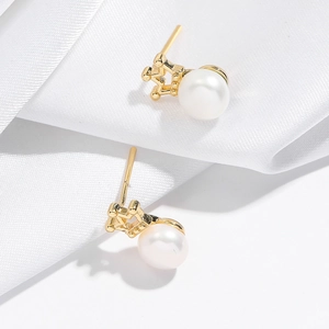 Elegant white freshwater pearl earrings with golden bases on silky white fabric background