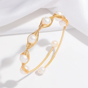 Detail of handmade wire-wrapped gold bracelet with natural pearls and woven design