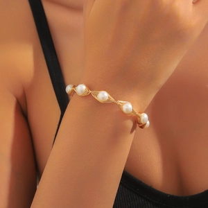 Detail of handmade gold wire-wrapped bracelet featuring natural white pearls on wrist