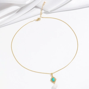 Détail du collier doré avec pierre turquoise, perle ronde et design en filigrane
