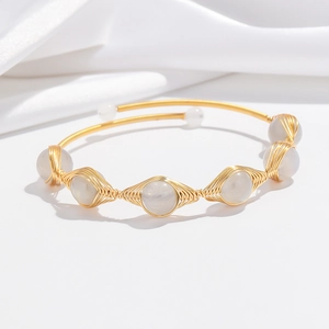 Detail of gold wire wrapped open bangle with white quartz beads in bohemian style