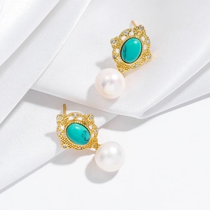 Vue détaillée de boucles d'oreilles rétro dorées avec turquoise et perles blanches