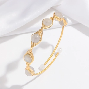 Detail of gold handmade wire-wrapped open cuff with five translucent gray gemstones