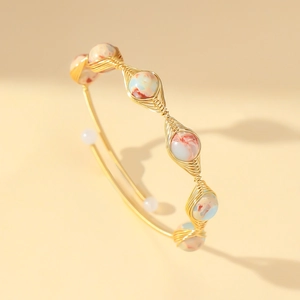 Detailed close-up of handmade gold wire-wrapped bangle with colorful gemstone beads