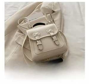 Vue détaillée du mini sac à dos crème avec boucle en métal et nœuds décoratifs en cuir
