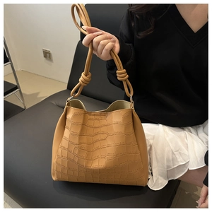 Dettaglio della trama a coccodrillo marrone e dell'elegante manico annodato su una borsa