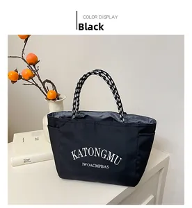 Detail of waterproof black nylon tote bag featuring woven rope handles and brand lettering