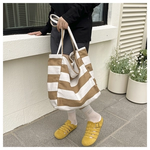 Detail of spacious canvas tote bag with brown and white horizontal stripes and long straps