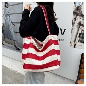 Detail of red and white striped canvas tote bag showing large capacity and red shoulder straps