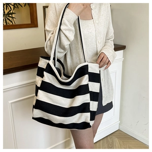 Detail of a large black and white striped canvas tote bag worn in a casual lifestyle setting