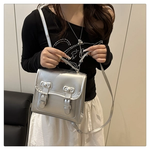 Close-up of silver metallic handbag with bow details and mirror shine texture