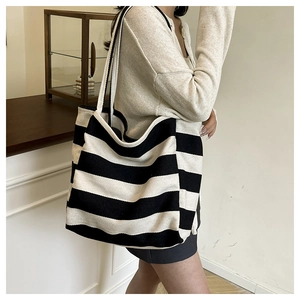 Close-up of black and white striped canvas tote bag worn on shoulder by a model