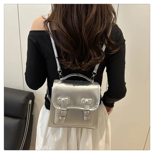 Silver bow backpack with metal texture shown on a model in a minimalist setting