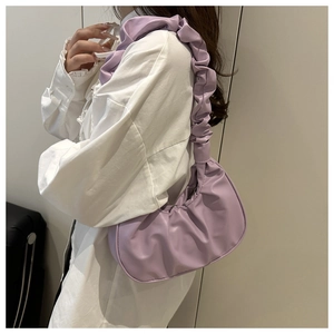 Detail of the lavender pleated dumpling bag with a scrunchie shoulder strap on model