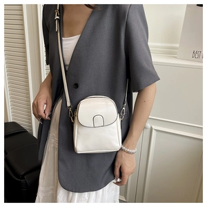 Modern creamy white crossbody phone bag shown on a model with a gray blazer and white dress