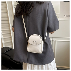 Adjustable shoulder strap detail on a beige PU leather mini crossbody phone bag