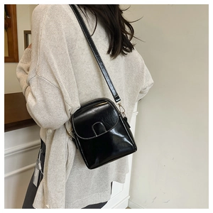 Close-up of black crossbody phone bag with contrast white stitching on premium glossy leather