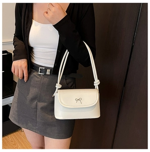 Détail d'un sac blanc à bandoulière avec boucle argentée et bretelles à nœuds élégants