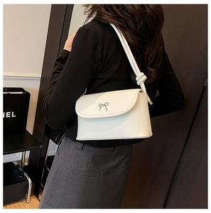 Vue latérale d'un sac à bandoulière blanc avec nœud argenté et détail de sangle nouée