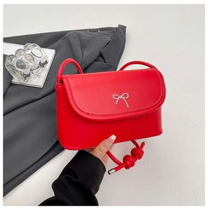 Détail du sac bandoulière rouge avec nœud argenté et bandoulière en cuir noué