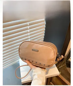 Detail of khaki leather oval crossbody bag with silver studs and adjustable strap