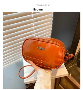 Detail of a brown glossy crossbody bag with JING PIN logo and round metal studs