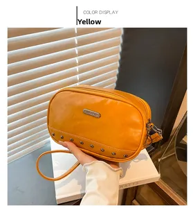 Detail showing yellow PU leather crossbody bag with metal JING PIN logo and rivets