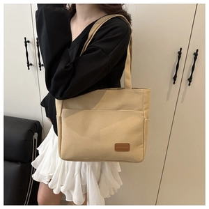 Close-up of khaki canvas tote bag featuring a practical front pocket and leather logo tag