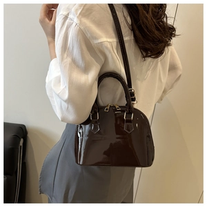 Detail of dark coffee patent leather shell bag showing glossy finish and gold hardware