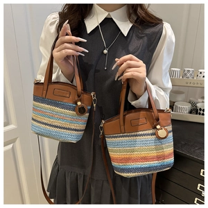 Close-up of woven bucket bag featuring rainbow stripes and brown leather handle