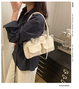 Detail of cream white shoulder bag featuring twin front pockets and lace bow accents