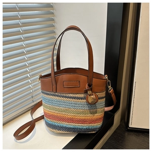 Detail of a woven bucket bag with color-block stripes and brown leather handles