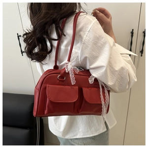 Detail of red faux leather shoulder bag with white lace bow and dual front pockets
