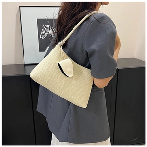 Close-up of cream woven shoulder bag with a knot detail and matching mini coin purse