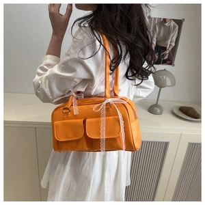 Close-up of bright orange faux leather shoulder bag with white lace bows and double pockets