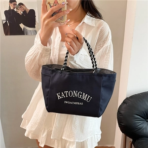 Waterproof navy blue nylon tote bag with woven handles and white letter print