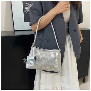 Detailed shot of silver woven shoulder bag with a matching charm on a model