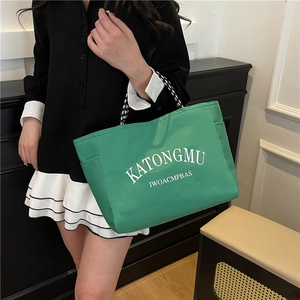 Green nylon tote bag with printed text and rope handles shown in a lifestyle setting