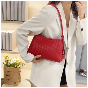 Detail of red woven shoulder bag with knotted strap shown on model in white blazer