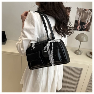 Detail of black PU leather shoulder bag with white lace bow on the shoulder strap