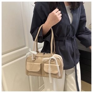 Detail of beige faux leather shoulder bag with bow accents and dual front magnetic pockets